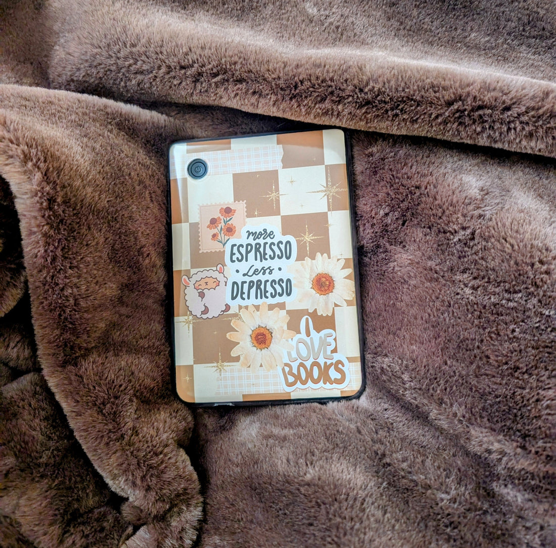 A kobo clara bw decorated with a clear case and a beautiful checkered cream and white insert with stickers. The Kobo is on a fluffy brown fur blanket, perfect for cosy nights in reading