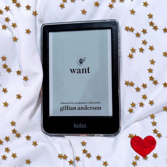 The cover of Want by Gillian Anderson on the screen of a black Kobo Clara E-reader on white bedsheets with stars and love hearts in the background to symbolize love and desire